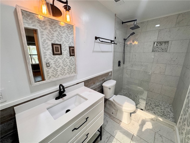 bathroom with a tile shower, vanity, and toilet