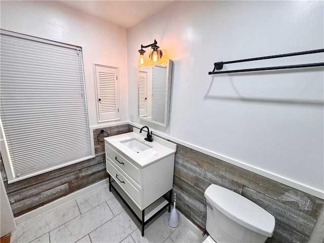 bathroom featuring vanity, toilet, and tile walls