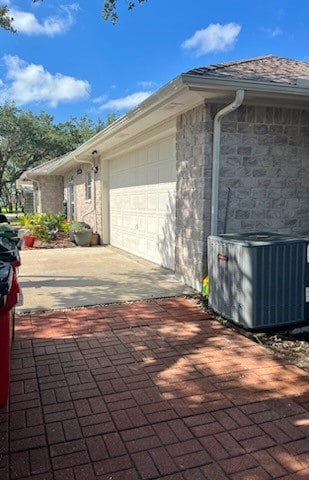 view of property exterior with central air condition unit and a garage