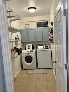 laundry area with cabinets, light tile patterned flooring, and washer and dryer