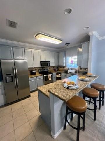 861 Redwood Ave, Rockport, TX 78382 - kitchen with stainless steel appliances, gray cabinets, ornamental molding, a peninsula, and a kitchen breakfast bar