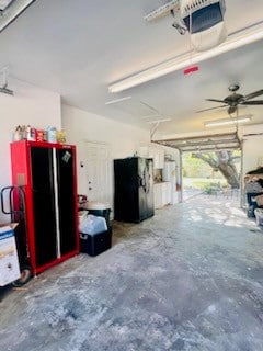 garage with a garage door opener, ceiling fan, and black fridge