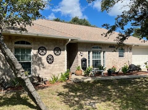 861 Redwood Ave, Rockport, TX 78382 - ranch-style house featuring a garage, stone siding, and a front lawn