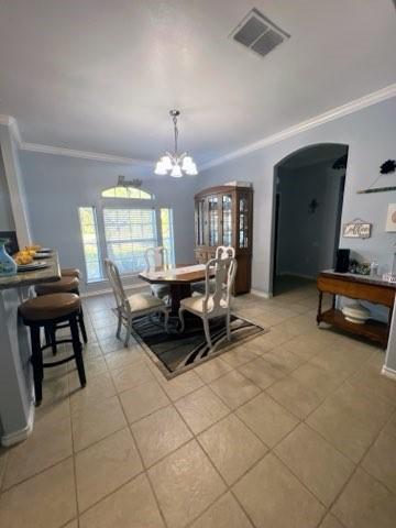 861 Redwood Ave, Rockport, TX 78382 - dining room featuring crown molding, arched walkways, a chandelier, and light tile patterned flooring