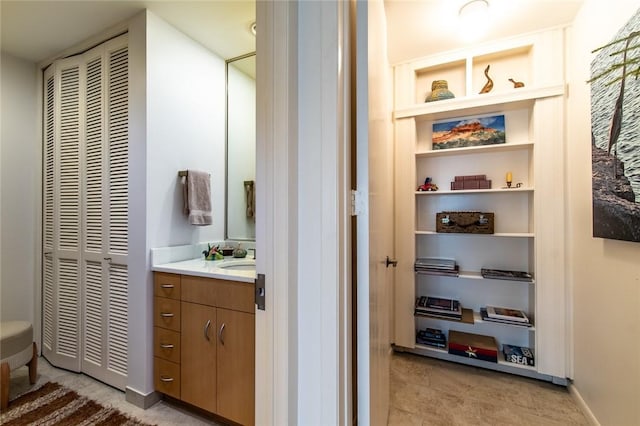 bathroom with built in shelves, baseboards, a closet, and vanity