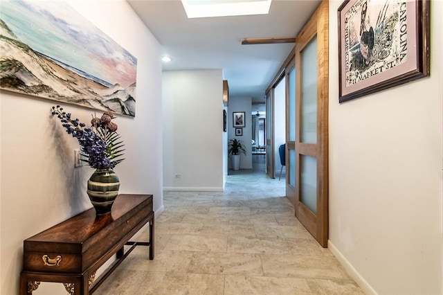 hall with a skylight and baseboards