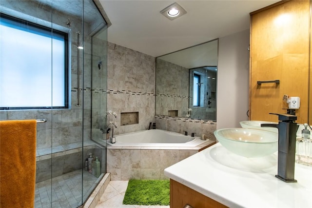 bathroom featuring a garden tub, a sink, tile walls, a shower stall, and double vanity