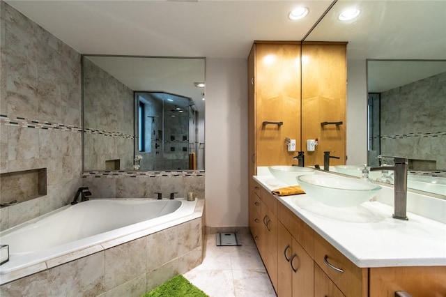 full bathroom with double vanity, tile walls, a sink, a shower stall, and a bath