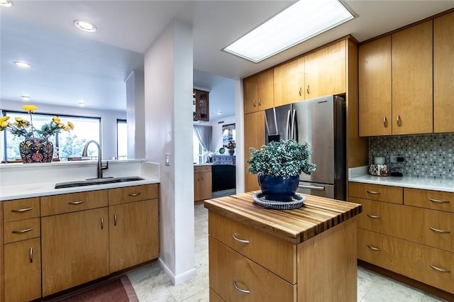 kitchen featuring a center island, tasteful backsplash, butcher block counters, a sink, and stainless steel fridge with ice dispenser