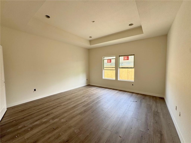 spare room featuring dark hardwood / wood-style flooring and a raised ceiling