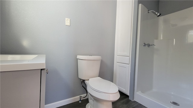 bathroom featuring hardwood / wood-style floors, walk in shower, vanity, and toilet