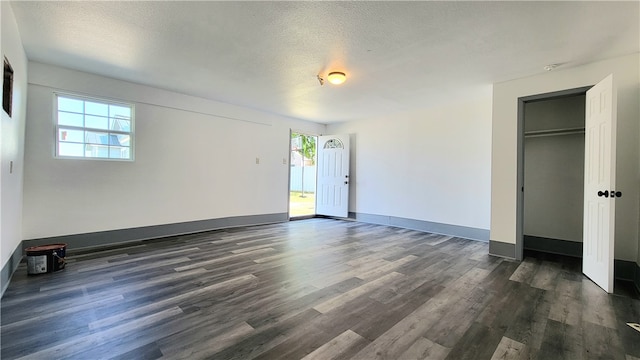 interior space featuring a closet, multiple windows, a textured ceiling, and dark hardwood / wood-style floors