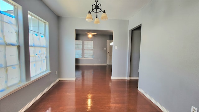 unfurnished dining area featuring dark hardwood / wood-style flooring, a healthy amount of sunlight, and an inviting chandelier