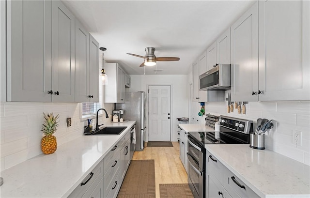 15209 Dasmarinas Dr, Corpus Christi, TX 78418 - kitchen with appliances with stainless steel finishes, a ceiling fan, backsplash, light wood-type flooring, and light stone counters