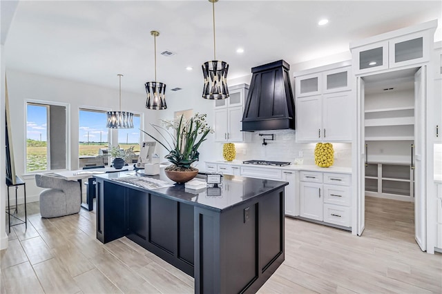 kitchen featuring light hardwood / wood-style floors, white cabinetry, premium range hood, and a center island