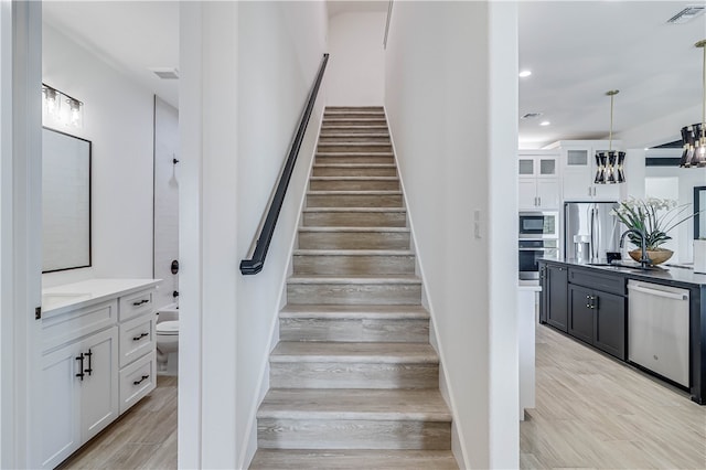 stairway with hardwood / wood-style flooring, sink, and an inviting chandelier