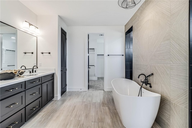 bathroom featuring tile walls, a bath, hardwood / wood-style flooring, and vanity