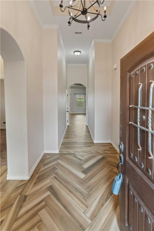 6913 Mets Ct, Corpus Christi, TX 78414 - entryway featuring arched walkways, crown molding, a chandelier, and baseboards