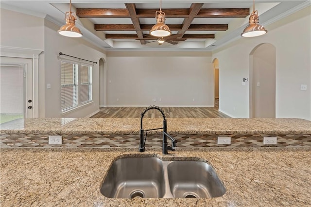 6913 Mets Ct, Corpus Christi, TX 78414 - kitchen with arched walkways, wood finished floors, a sink, beam ceiling, and light stone counters