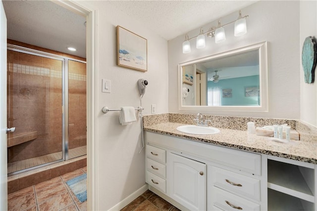 6317 State Highway 361 Unit 3312, Port Aransas, TX 78373 - bathroom featuring a shower stall, vanity, a textured ceiling, ceiling fan, and tile patterned flooring
