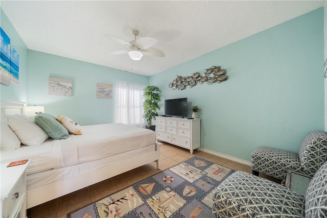 bedroom with light tile patterned flooring, ceiling fan, a textured ceiling, and baseboards