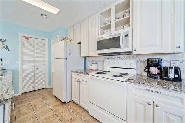 kitchen featuring white appliances, visible vents, white cabinets, backsplash, and light stone countertops