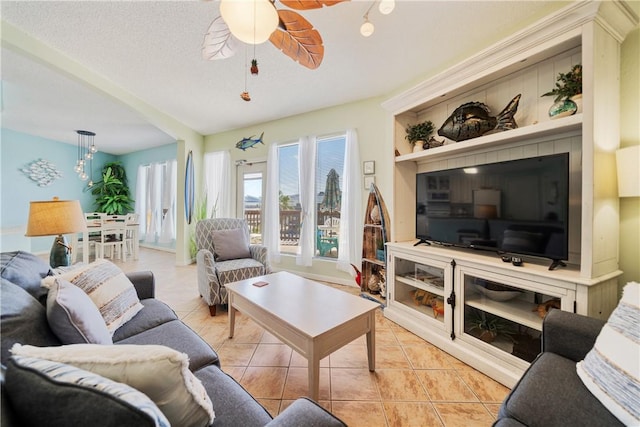 living room with light tile patterned floors, ceiling fan, and a textured ceiling