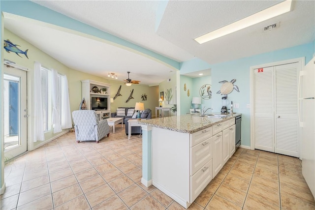 kitchen featuring light tile patterned floors, a peninsula, a sink, visible vents, and stainless steel dishwasher