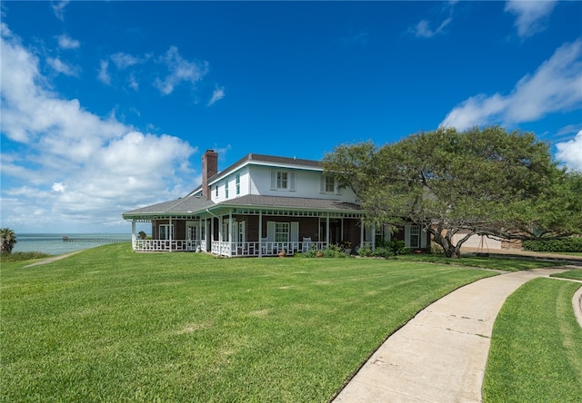 back of house with a lawn, covered porch, and a water view