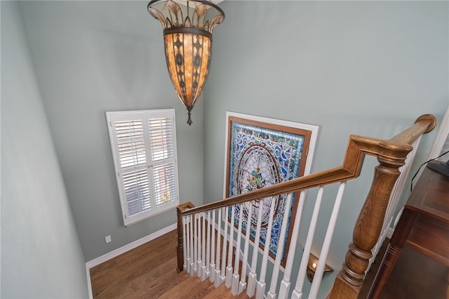 stairs with hardwood / wood-style flooring and an inviting chandelier