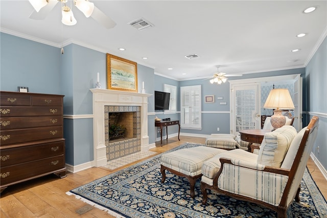 living room with a fireplace, ceiling fan, light hardwood / wood-style flooring, and ornamental molding