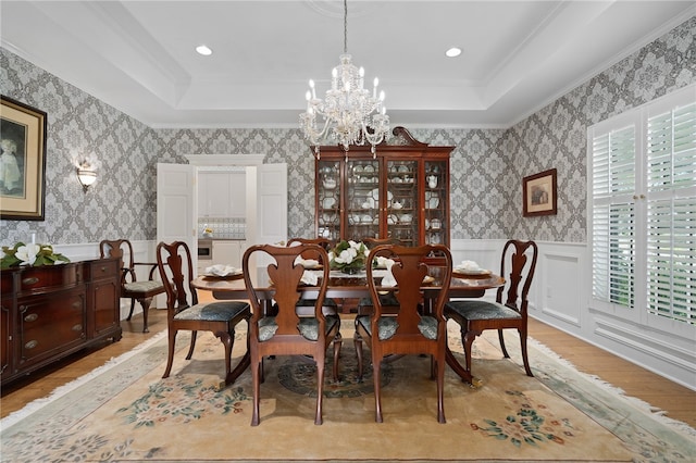 dining area with ornamental molding, a wealth of natural light, light hardwood / wood-style flooring, and a raised ceiling