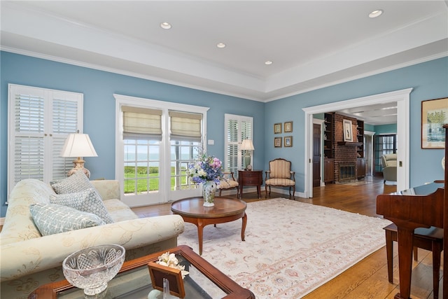 living room featuring hardwood / wood-style floors, ornamental molding, and a brick fireplace