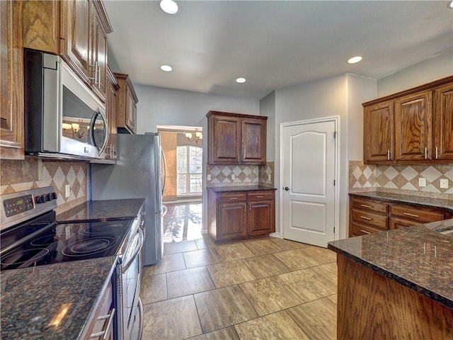 kitchen with appliances with stainless steel finishes, tasteful backsplash, and dark stone counters