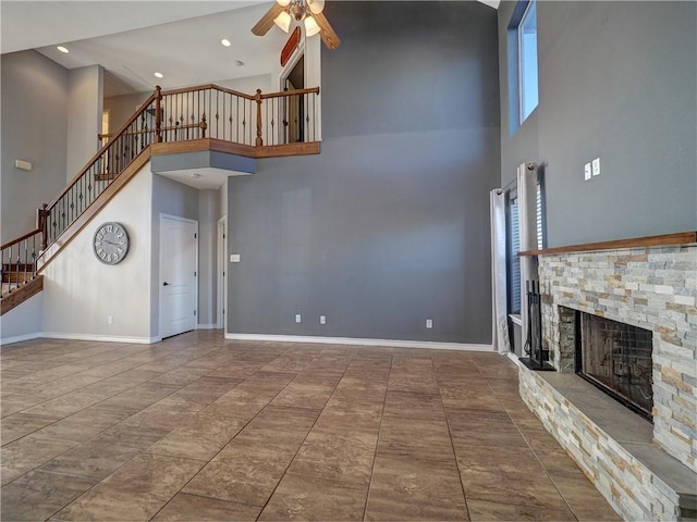 unfurnished living room with a fireplace, a high ceiling, and ceiling fan