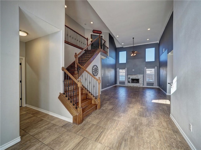 foyer entrance featuring ceiling fan, a wealth of natural light, a fireplace, and a high ceiling