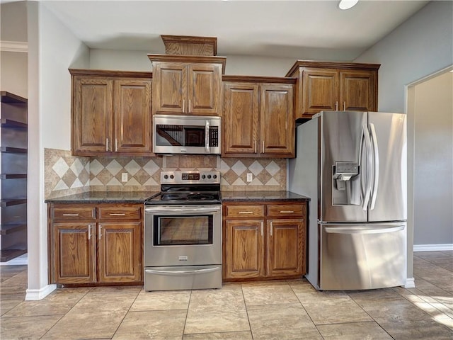 kitchen featuring appliances with stainless steel finishes, tasteful backsplash, dark stone counters, and light tile patterned flooring