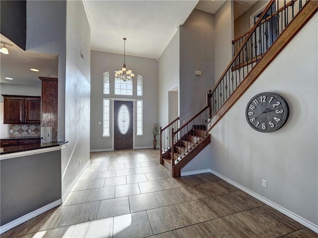 foyer featuring a towering ceiling, crown molding, and an inviting chandelier