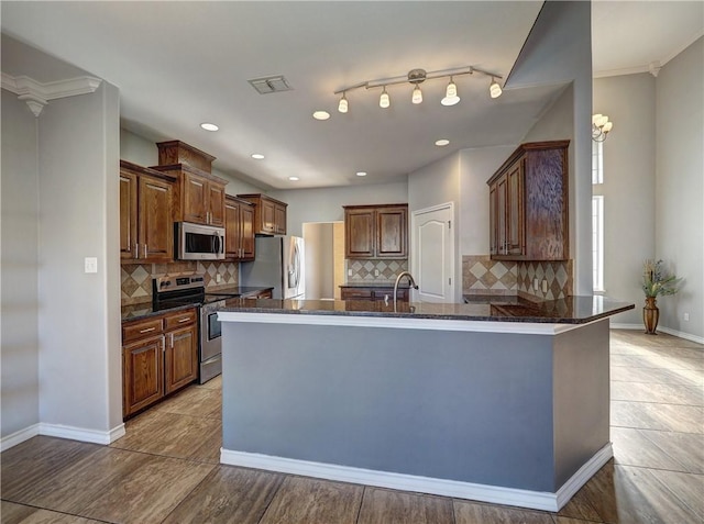 kitchen featuring kitchen peninsula, decorative backsplash, dark stone counters, stainless steel appliances, and sink