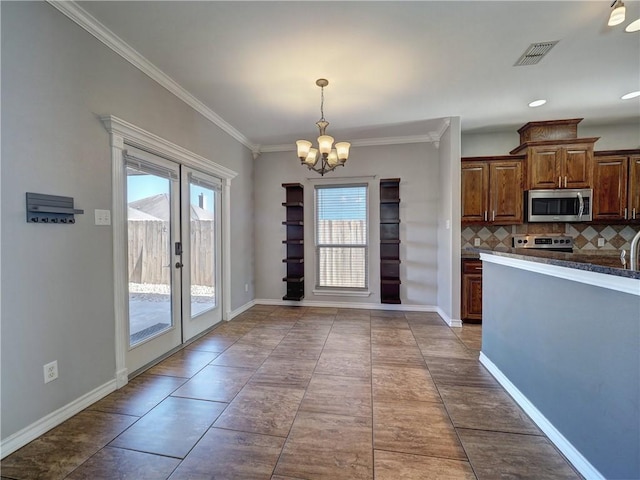 kitchen featuring stove, french doors, tasteful backsplash, dark tile patterned flooring, and a notable chandelier