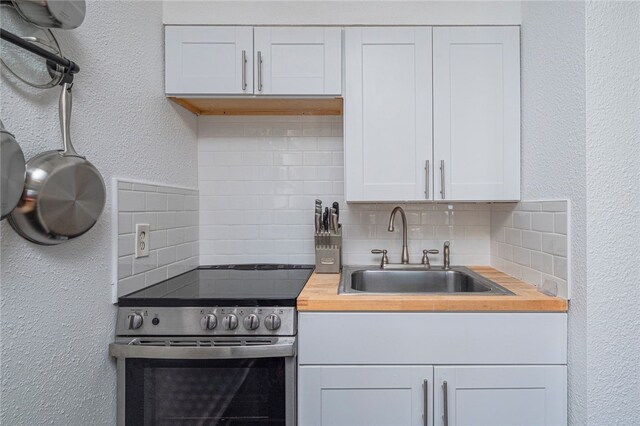 3938 Surfside Blvd Unit 3116, Corpus Christi, TX 78402 - kitchen featuring stainless steel electric range oven, a sink, tasteful backsplash, wooden counters, and white cabinetry
