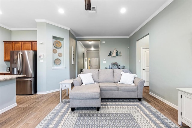 living room featuring visible vents, light wood-style flooring, crown molding, and baseboards