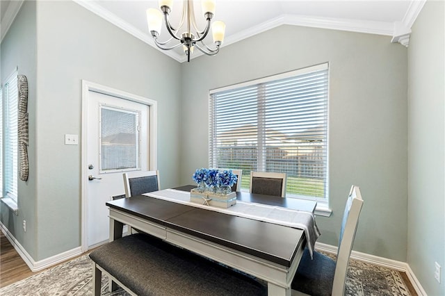 dining space featuring light wood finished floors, crown molding, baseboards, vaulted ceiling, and a notable chandelier