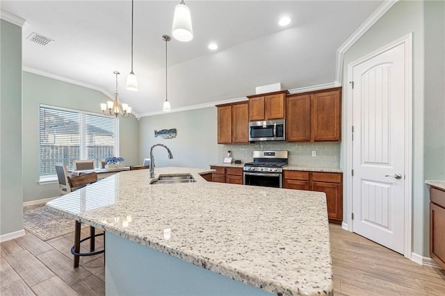 kitchen with ornamental molding, stainless steel appliances, light wood-style floors, and a sink