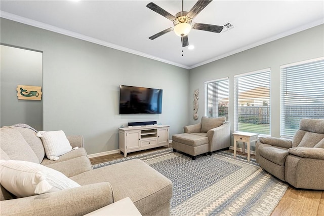 living area with a ceiling fan, baseboards, visible vents, light wood-style flooring, and ornamental molding