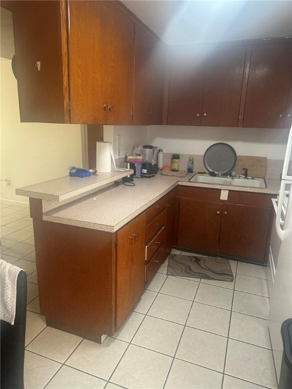 kitchen featuring kitchen peninsula, light tile patterned flooring, and sink