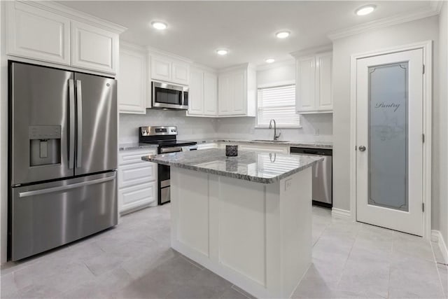 1501 Days End Dr, Corpus Christi, TX 78417 - kitchen with stainless steel appliances, ornamental molding, white cabinetry, light stone counters, and a kitchen island