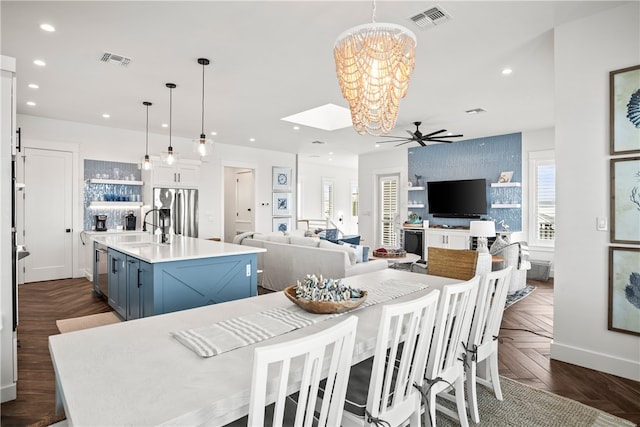 dining space featuring sink, dark parquet flooring, and ceiling fan with notable chandelier