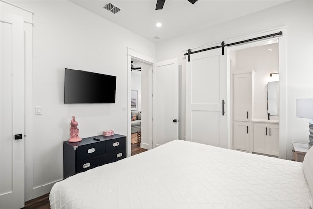 bedroom with a barn door, ceiling fan, and dark hardwood / wood-style floors