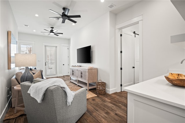 living room with dark wood-type flooring, a barn door, sink, and ceiling fan